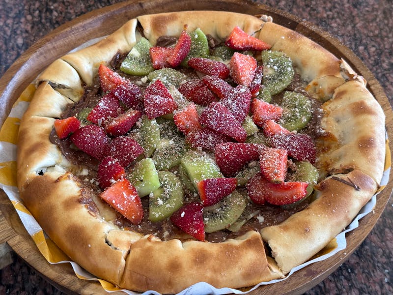 Warm Nutella and strawberry dessert pizza with powdered sugar